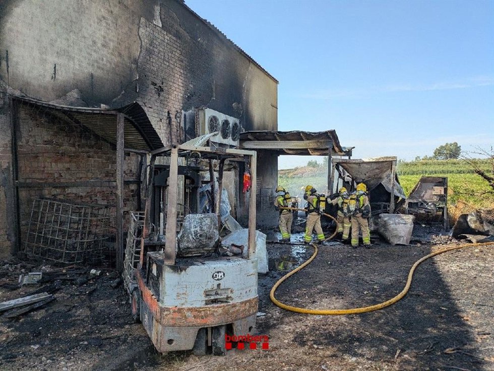 Los Bombers de la Generalitat trabajan en la extinción de un incendio en una nave de Lleida