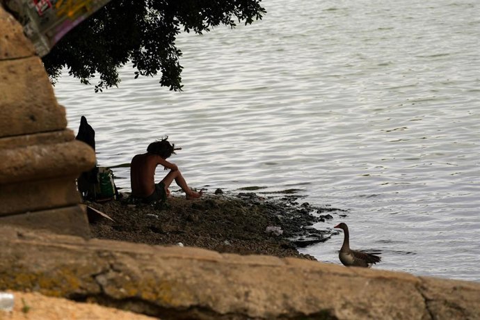 Archivo - Una persona descansa junto al río, en Sevilla (Andalucía, España). 
