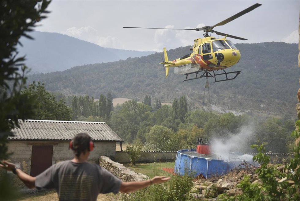Helicóptero recoge agua de una piscina de plástico en Atarés  durante las labores de extinción de un incendio forestal, a 16 de agosto de 2026, en Las Peñas de Riglos, Huesca, Aragón (España). 