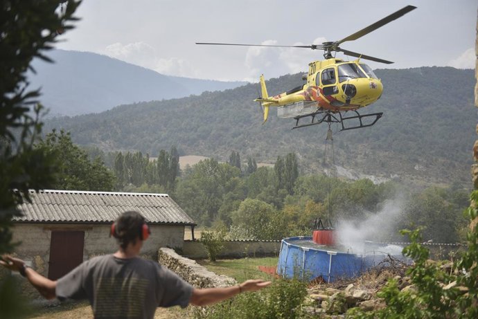 Helicóptero recoge agua de una piscina de plástico en Atarés  durante las labores de extinción de un incendio forestal, a 16 de agosto de 2026, en Las Peñas de Riglos, Huesca, Aragón (España). El operativo desplazado al incendio forestal de Las Peñas de R