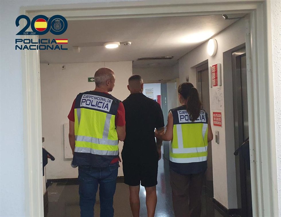 El detenido, de espaldas y escoltado por dos agentes de la Policía Nacional.
