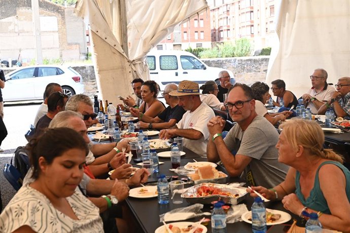 Pessoas evacuadas devido a um incêndio florestal fazem uma refeição no centro esportivo de Ayerbe, em 14 de agosto de 2026, em Las Peñas de Riglos, Hoya de Huesca, Huesca, Aragão (Espanha). O incêndio, que começou às 12h37 desta segunda-feira em Las Peñas