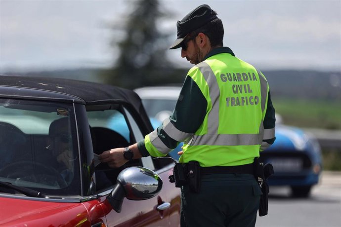 Archivo - Un agente de la Guardia Civil pide documentación a un conductor  en un control de tráfico