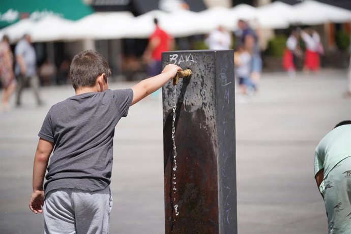 Archivo - Un niño llena usa una fuente para refrescarse