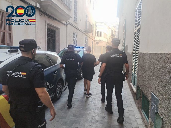 O detido, de costas, escoltado por vários policiais da Polícia Nacional.