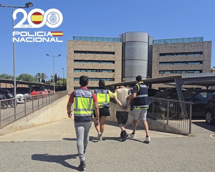 El detenido, de espaldas y escoltado por tres agentes de la Policía Nacional.