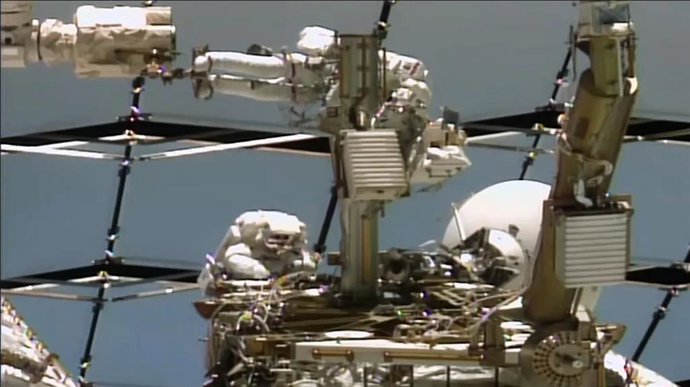 De arriba abajo, los astronautas Anil Menon de la NASA y Sophie Adenot de la ESA (Agencia Espacial Europea) trabajan en una antena de comunicación espacio-tierra en el exterior de la Estación Espacial Internacional.