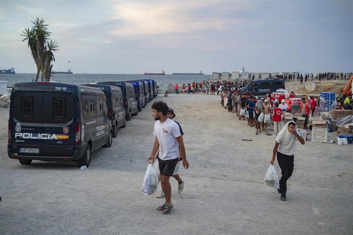 Varios inmigrantes hacen cola para que les den comida en una playa, a 19 de agosto de 2026, en Ceuta (España). C