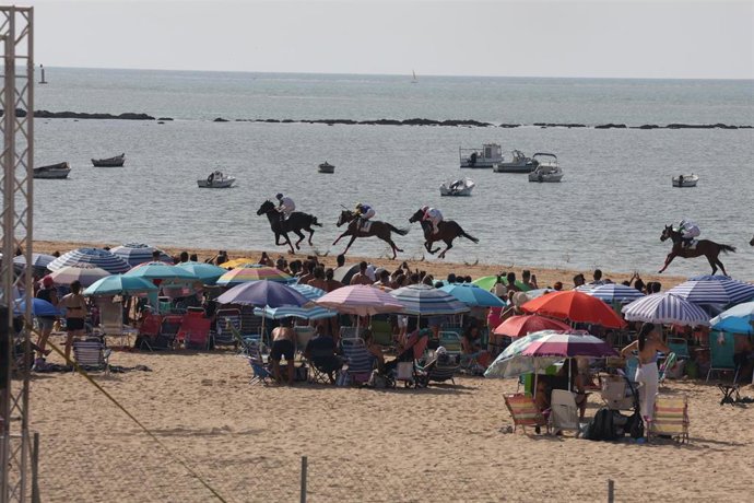 La carreras de caballos de Sanlúcar de Barrameda con bañistas en la playa de las Piletas durante el primer ciclo. A 8 de agosto de 2026 en Sanlúcar de Barrameda (Cádiz, Andalucía, España). ARCHIVO