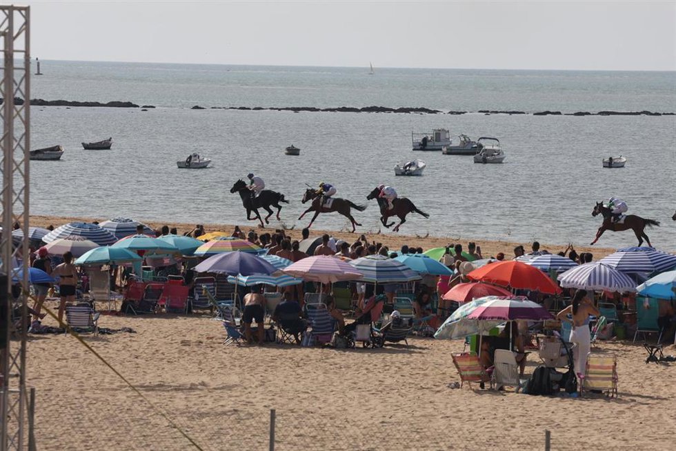 La carreras de caballos de Sanlúcar de Barrameda con bañistas en la playa de las Piletas durante el primer ciclo. A 8 de agosto de 2026 en Sanlúcar de Barrameda (Cádiz, Andalucía, España). ARCHIVO