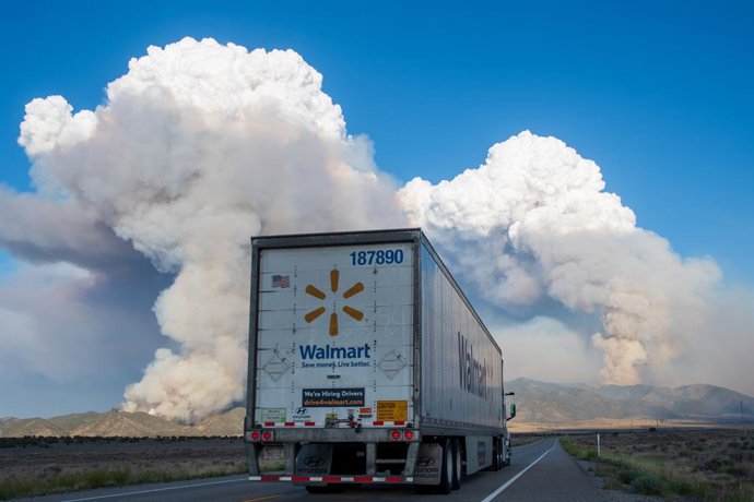 Archivo - Arquivo - 21 de junho de 2026, Saratoga Springs, Utah, EUA: Um caminhão do Walmart segue em direção às enormes colunas de fumaça do incêndio Iron Fire, que queima nas Montanhas East Tintic, perto de Eureka. O incêndio florestal já queimou mais d