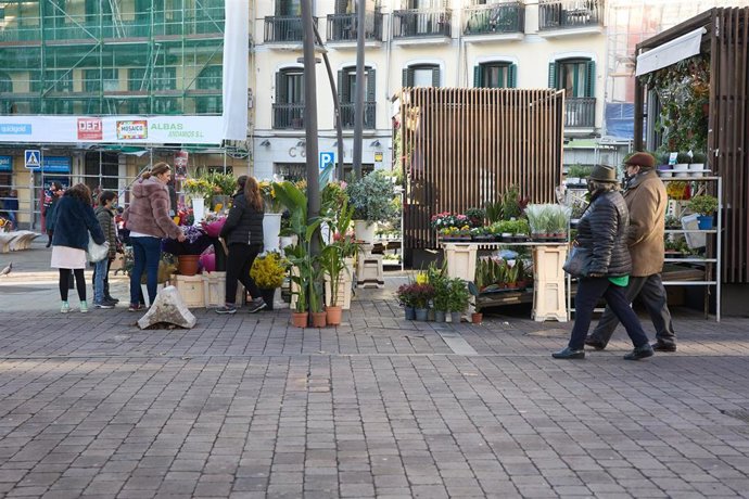 Archivo - Una mujer compra flores en un puesto en la plaza de Tirso de Molina en Madrid.