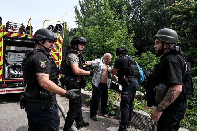 Agentes de la Policía Nacional ucraniana atienden a un hombre herido en una empresa industrial alcanzada por una bomba aérea guiada rusa en Zaporiyia.