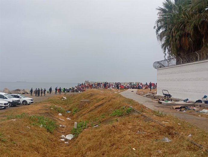 Migrantes aguardan en los alrededores de la playa de El Trampolín mientras los equipos de limpieza higienizan la zona