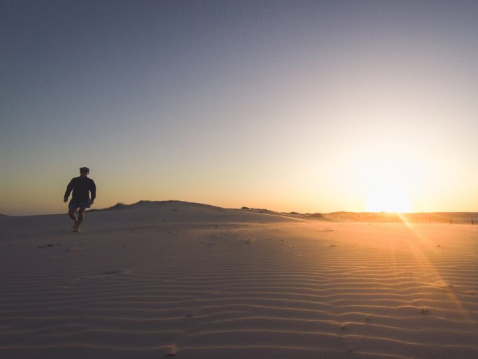 Hombre pasea por el desierto al atardecer
