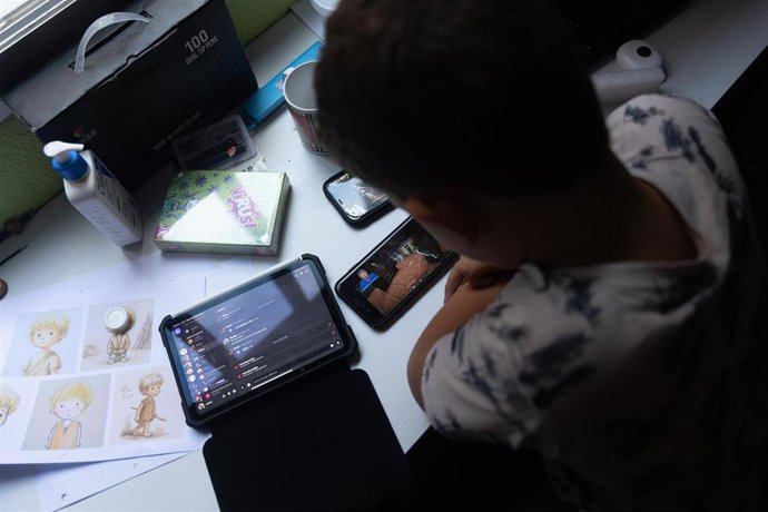 Archivo - Un niño usa el teléfono móvil y una tablet, a 18 de octubre de 2023, en Madrid (España). 