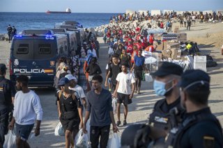 Miembros de la Cruz Roja atienden a varios inmigrantes, en la playa del Trampolín, a 20 de agosto de 2026, en Ceuta (España).