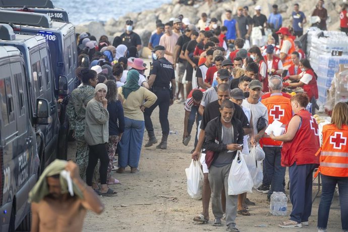 Miembros de la Cruz Roja atienden a varios inmigrantes, en la playa del Trampolín, a 20 de agosto de 2026, en Ceuta (España). 