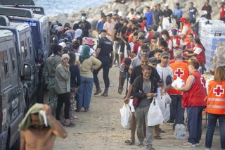 Miembros de la Cruz Roja atienden a varios inmigrantes, en la playa del Trampolín, a 20 de agosto de 2026, en Ceuta (España). El Ministerio de Defensa ha aprobado que más de un centenar de militares procedentes de Canarias se desplacen a Ceuta para reforz