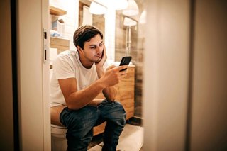 Archivo - Imagen de recurso de un hombre en el baño mirando el móvil.