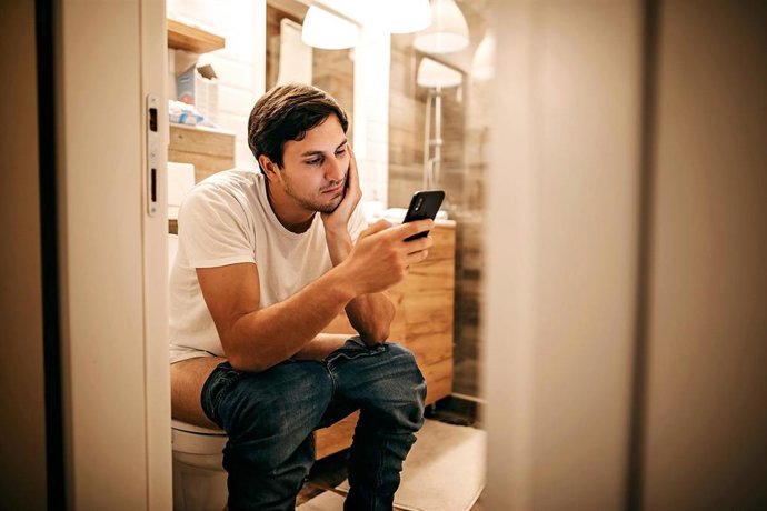 Archivo - Imagen de recurso de un hombre en el baño mirando el móvil.