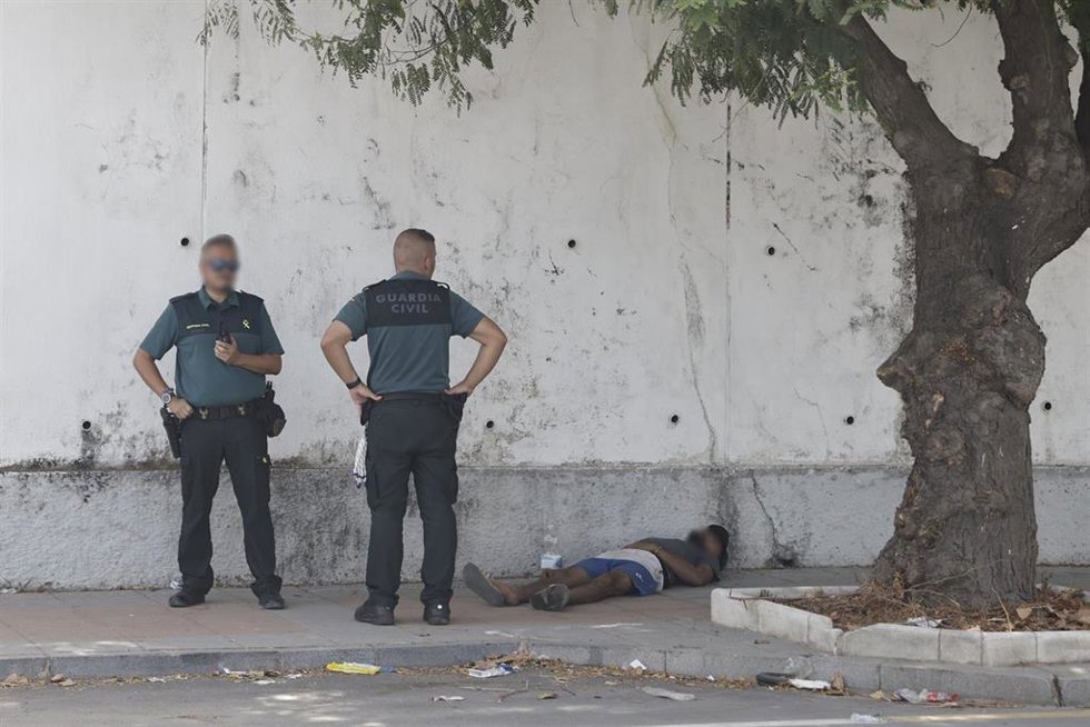 Dos agentes de la Guardia Civil observan a una persona tumbada, a 1 de agosto de 2026, en Ceuta (España). 