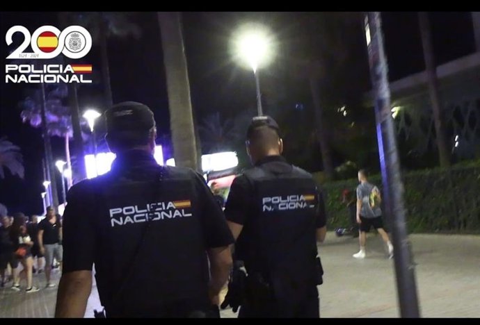 Dos agentes de la Policía Nacional, de espaldas.