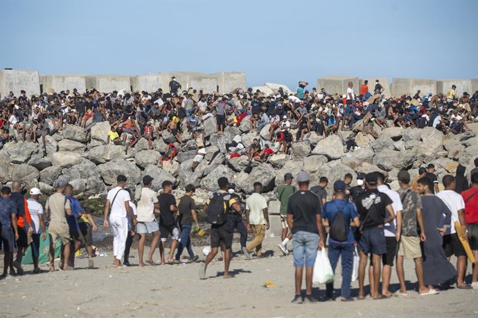 Membros da Cruz Vermelha distribuem comida aos imigrantes em uma praia, em 21 de agosto de 2026, em Ceuta (Espanha). Ceuta continua enfrentando uma grave crise humanitária após a histórica chegada em massa de mais de 70 mil migrantes, que atravessaram a n