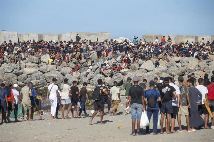 Miembros de la Cruz Roja reparten comida a los inmigrantes en una playa, a 21 de agosto de 2026, en Ceuta (España). 
