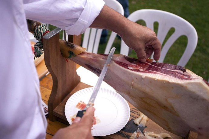 Archivo - Un maestro cortador despieza un jamón en Monesterio.