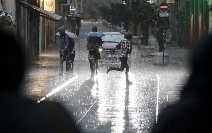 Archivo - Varias personas caminan bajo la lluvia, en imagen de archivo. 