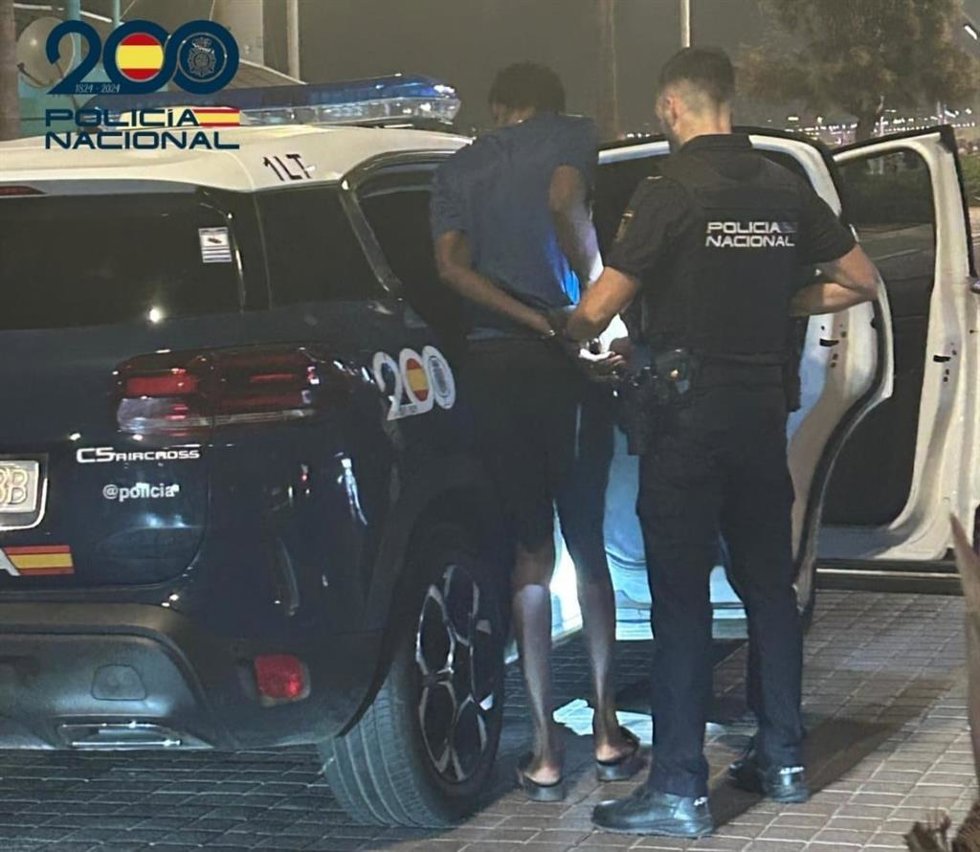 El detenido ingresa en una patrulla policial escoltado por un agente de la Policía Nacional.