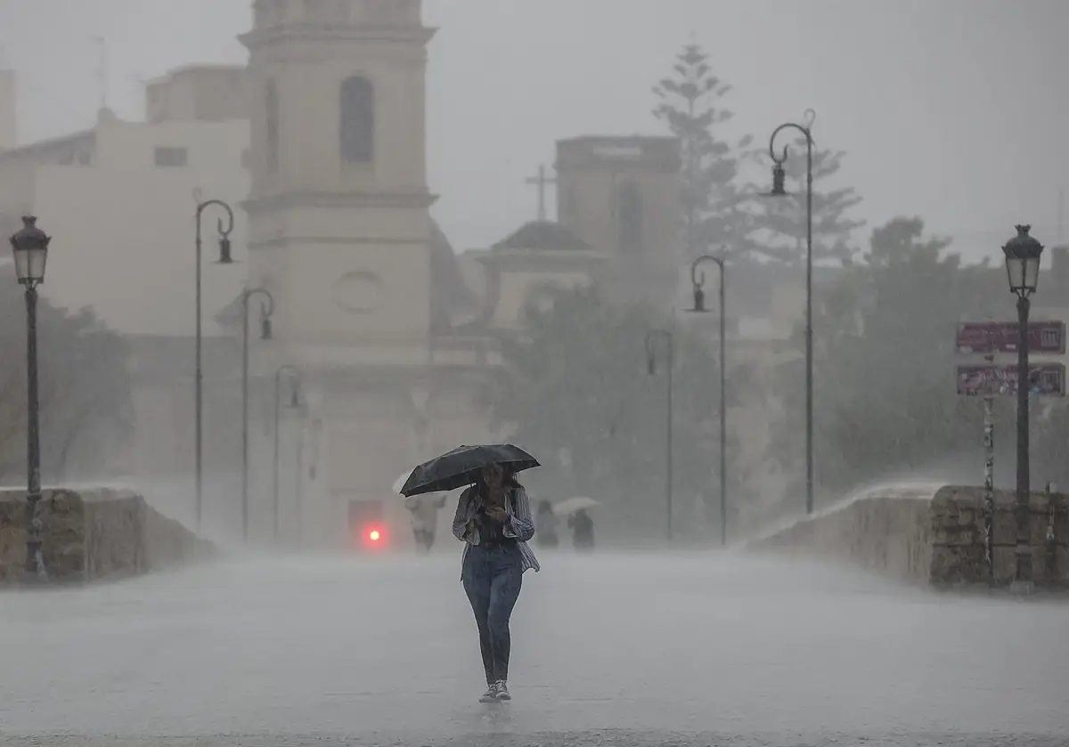 Una persona camina con un paraguas bajo la lluvia en imagen de archivo.