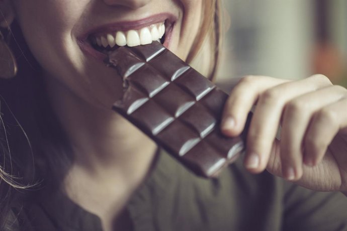 Archivo - Mujer comiendo una tableta de chocolate negro.