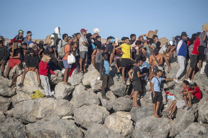 Miembros de la Cruz Roja reparten comida a los inmigrantes en una playa, a 21 de agosto de 2026, en Ceuta (España).