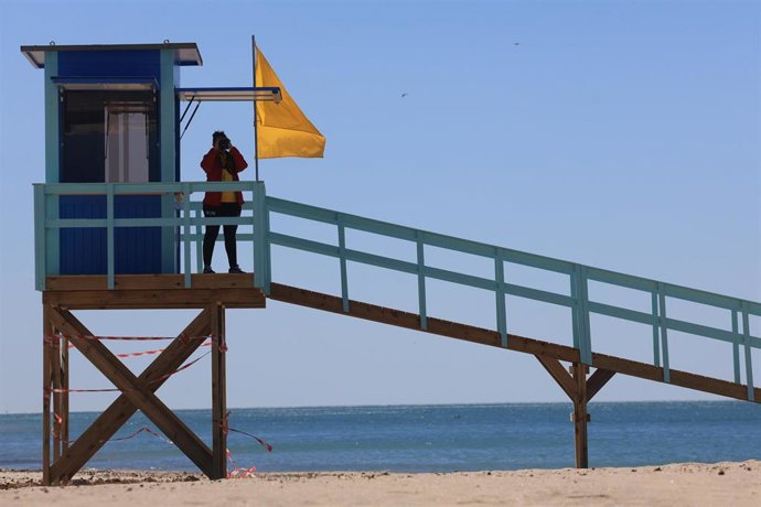 Archivo - Un socorrista con la bandera amarilla izada en una playa de Cádiz. ARCHIVO.
