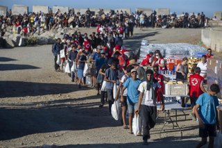 Miembros de la Cruz Roja reparten comida a los inmigrantes en una playa, a 21 de agosto de 2026, en Ceuta (España).