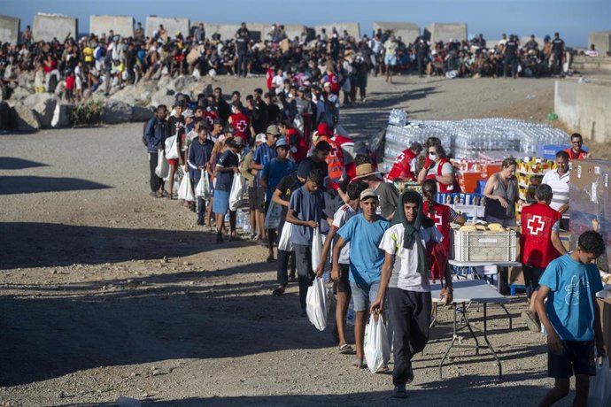 Miembros de la Cruz Roja reparten comida a los inmigrantes en una playa, a 21 de agosto de 2026, en Ceuta (España).