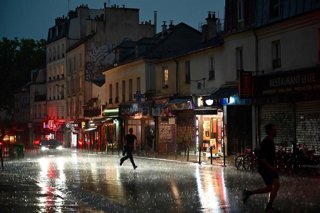 Archivo - 25 June 2025, France, Paris: People run for shelter on a street in the 20th Arrondissement during a thunderstorm. Photo: Christophe Delattre/AFP/dpa