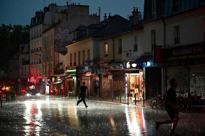 Archivo - 25 June 2025, France, Paris: People run for shelter on a street in the 20th Arrondissement during a thunderstorm. Photo: Christophe Delattre/AFP/dpa