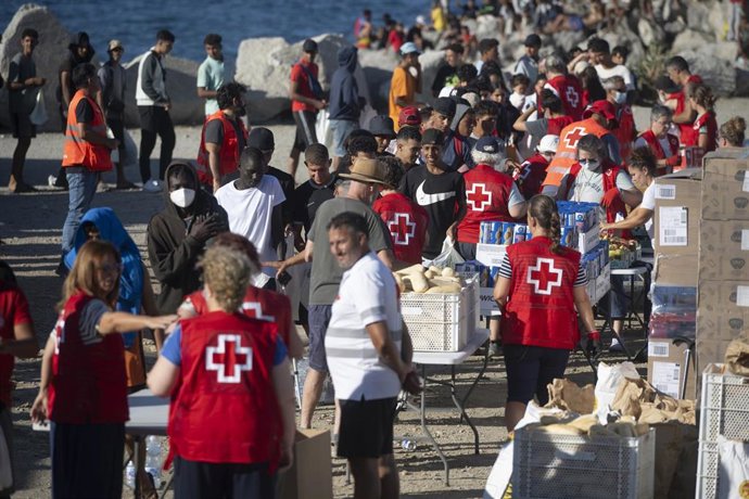Miembros de la Cruz Roja reparten comida a los inmigrantes en una playa, a 21 de agosto de 2026, en Ceuta (España). 
