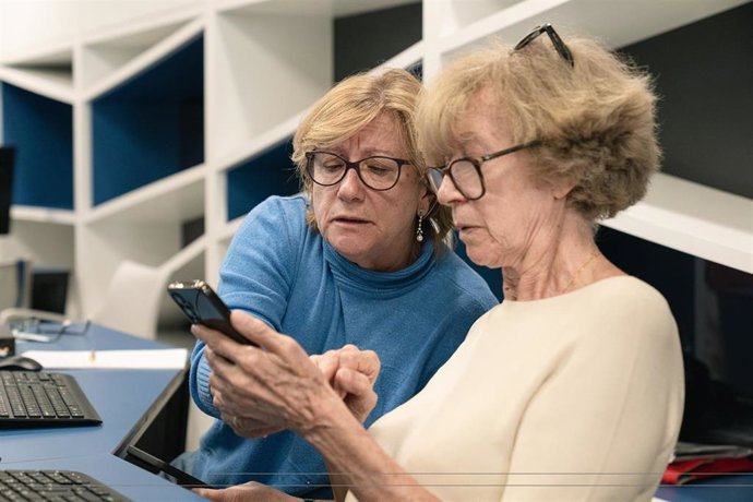 Dos mujeres utilizando un teléfono móvil.