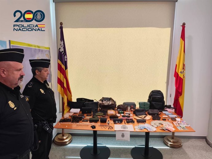 Dos agentes de la Policía Nacional, junto a varios de los efectos robados por los tres detenidos.