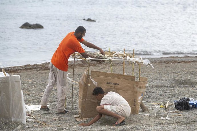 Varios migrantes vuelven a instalarse en la playa El Trampolín durante las tareas de limpieza, a 24 de agosto de 2026, en Ceuta (España). 
