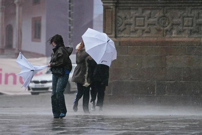 Archivo - Varias personas intentan sujetar sus paraguas, a 26 de enero de 2026, en Santiago de Compostela, A Coruña, Galicia (España).