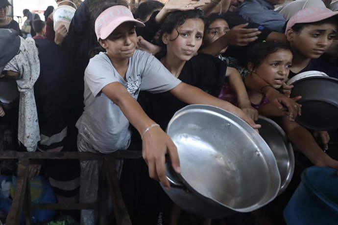 Palestinos desplazados se reúnen para recibir comidas de una cocina benéfica en el campamento de refugiados de Nuseirat, en el centro de la Franja de Gaza, el 16 de agosto de 2026.
