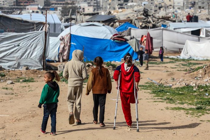 Archivo - Arquivo - GAZA, 28 de janeiro de 2026  -- A menina palestina Malak Khader (1ª à direita) caminha em um abrigo temporário a leste da cidade de Gaza, em 27 de janeiro de 2026. A menina de 9 anos perdeu a perna e tornou-se a única sobrevivente de s
