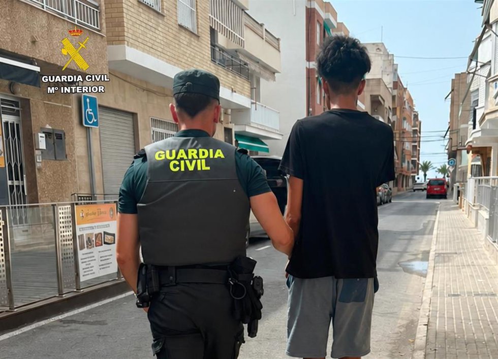 Un agente de la Guardia Civil custodia al detenido
