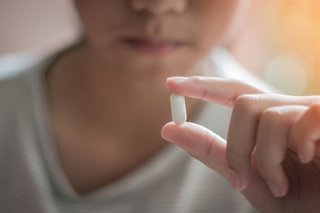 Archivo - Adolescente, joven con medicamento farmacológico, toma píldoras médicas para aliviar el dolor, paracetamol