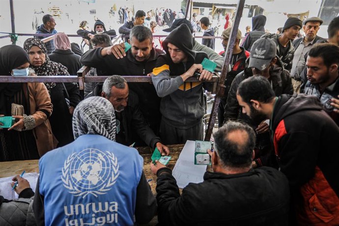 Archivo - Palestinos recibiendo ayuda de personal de UNRWA